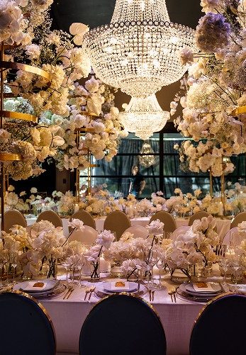 White wedding florals beneath crystal chandeliers